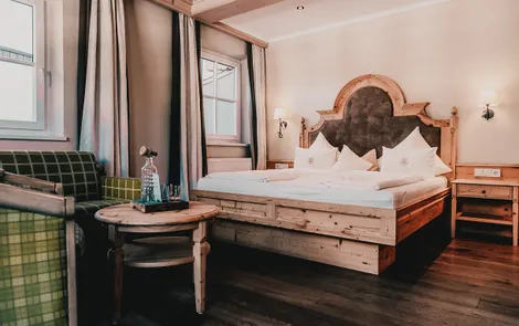 Bergglück Gemütliches Alpenhotelzimmer mit rustikalem Holzbett, grünen Sesseln und eleganter Einrichtung